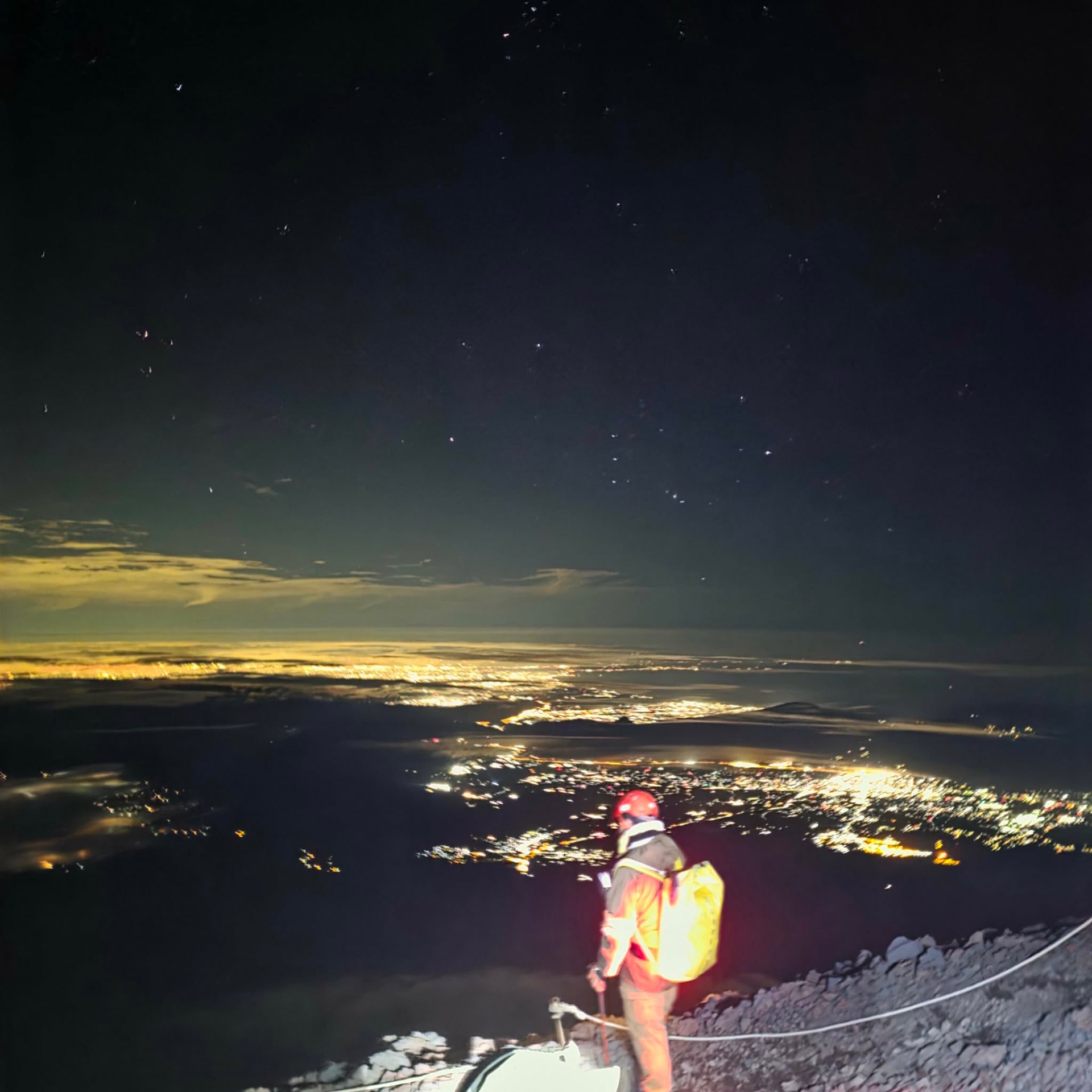 Night ascent on Mount Fuji, city lights far below.